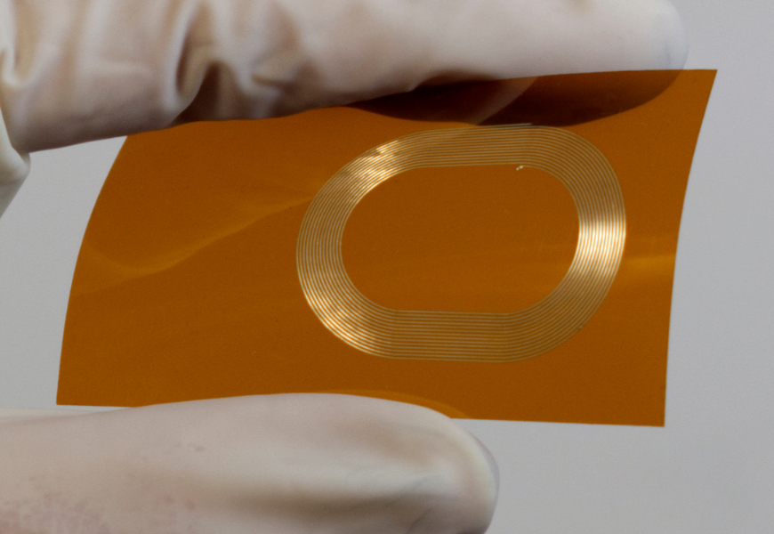 Picture of NanoJet aerosol printed conductive traces on kapton film that is held by gloved fingers